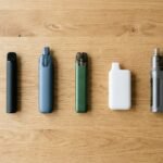 Five unbranded vape pens and disposables laid out on a wooden table